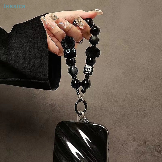 CasePoppi Black Cat Beaded Phone Strap being held, demonstrating the charm attached to a ripple-texture black phone case, unique techcessory.