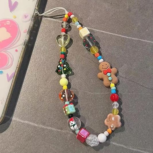 CasePoppi festive gingerbread man and Christmas tree beaded phone strap on a grey textured background, showcasing the colorful holiday-themed acrylic charms.