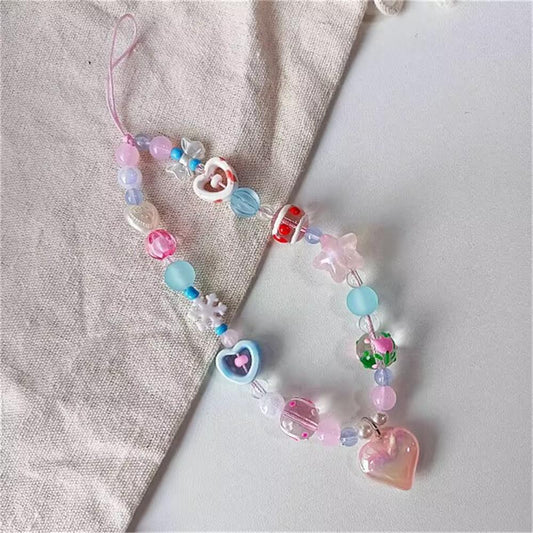 CasePoppi multi-color beaded phone strap lying on a light grey textured fabric surface, showcasing the playful arrangement of charms and unique translucent jelly bead effects.