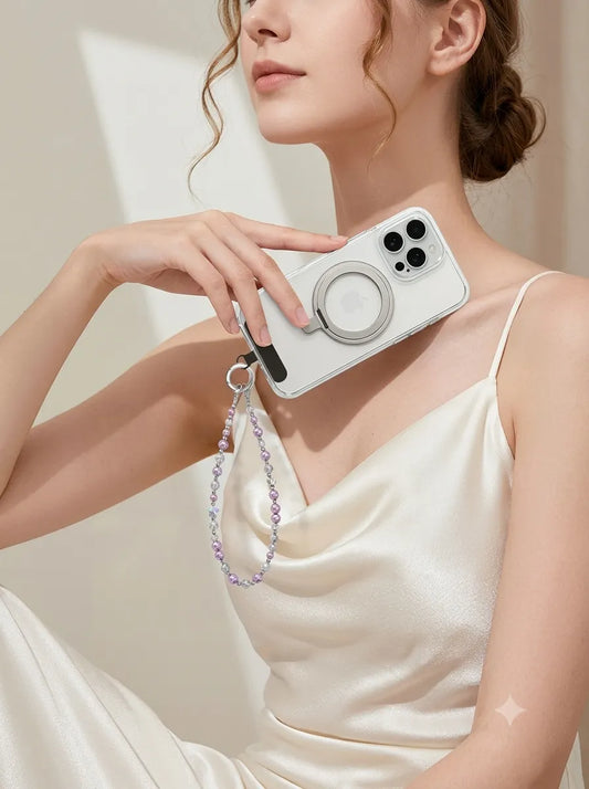 An elegant lifestyle photo of a woman in a white silk strap dress holding a white phone decorated with a delicate lilac crystal beaded phone charm.
