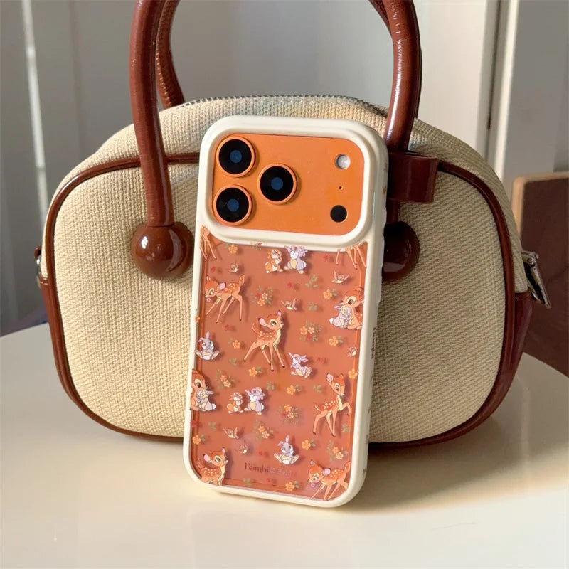 Aesthetic brown phone case for iPhone 17 Pro Max, featuring cute Bambi and woodland animal pattern, leaning against a cream woven tote bag, protective and cute style.