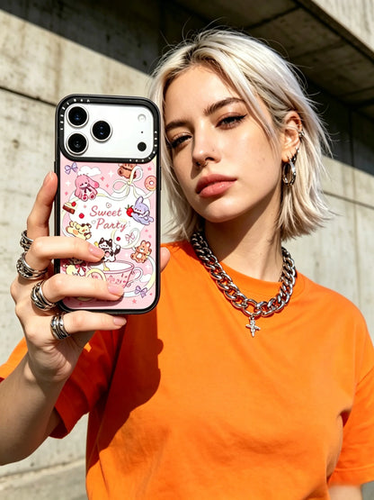 A vibrant outdoor lifestyle photo of a blonde woman in a bright orange t-shirt and chunky chain necklace, showcasing a pink graffiti style phone case.
