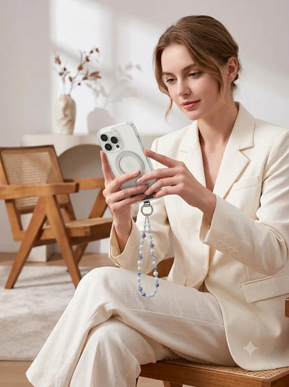 A professional chic lifestyle photo of a woman in a white blazer holding a magnetic phone with a dainty light blue crystal beaded phone charm attached.