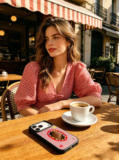 Woman holding red striped mirror phone case at cafe table