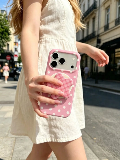 Woman holding white polka dot pink phone case on city street