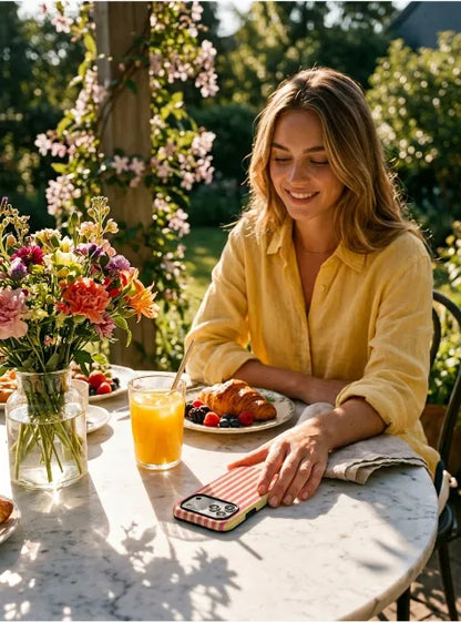 Woman holding coral yellow striped phone case at breakfast table