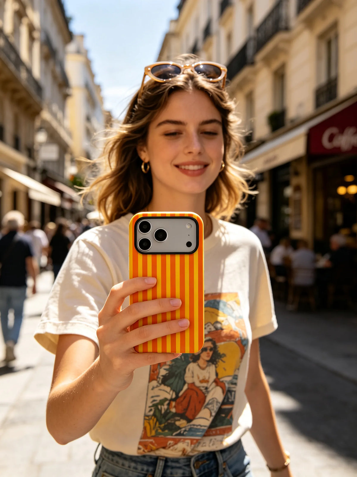 Woman holding tangerine orange striped phone case on city street